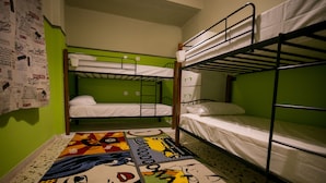 A dormitory room with bunk beds, a green wall, and a colorful comic strip rug.