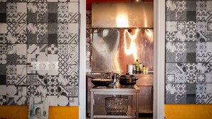 A kitchen with patterned tiles, a stainless steel range hood, and various cooking pots.