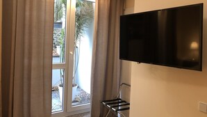A room with a sliding glass door, a flat-screen TV mounted on the wall, and a metal drying rack. - Gatow 183 (Berlin)