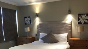 Ein Schlafzimmer mit einem großen Bett, zwei Nachttischen und Wandleuchten.