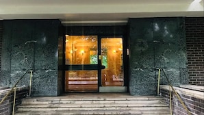 Una serie di gradini in pietra che conducono a una porta in vetro, con vista su una strada e alberi.