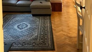 Un soggiorno moderno con un divano grigio, cuscini rossi, un tappeto fantasia e un tavolino in legno.