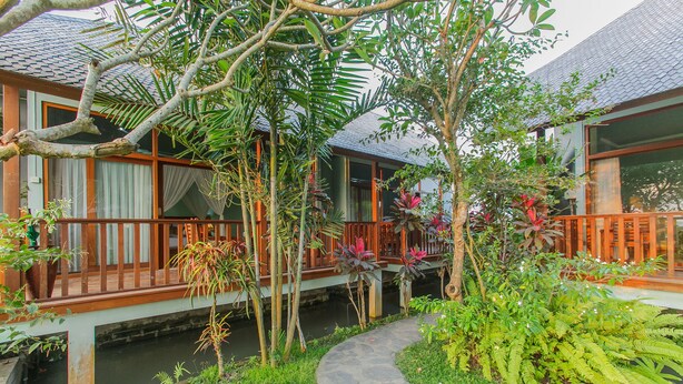 Une maison traditionnelle en bois, avec un chemin de pierre menant à un élément décoratif aquatique.