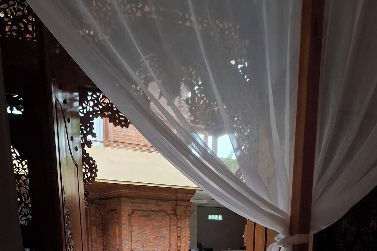 A room with a bed, a view of a swimming pool, and a brick structure outside.