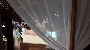 Une chambre avec un lit, une vue sur une piscine et une façade en briques.