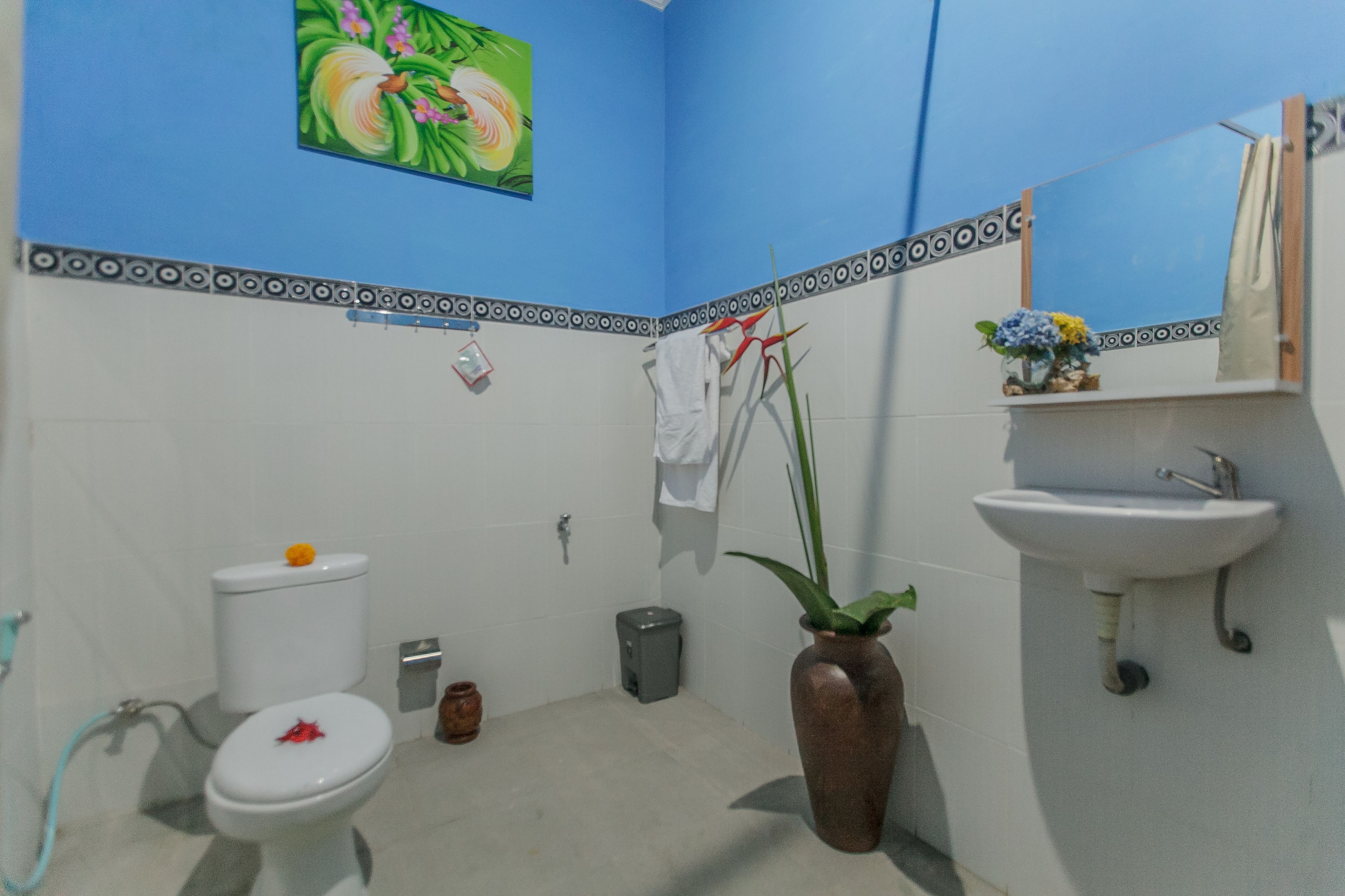 Un baño con inodoro, lavamanos, espejo y plantas decorativas.