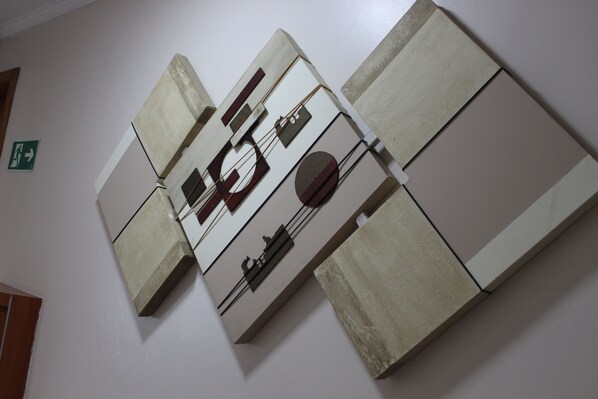 Une œuvre d’art abstraite, fixée au mur, composée de formes et de lignes géométriques.