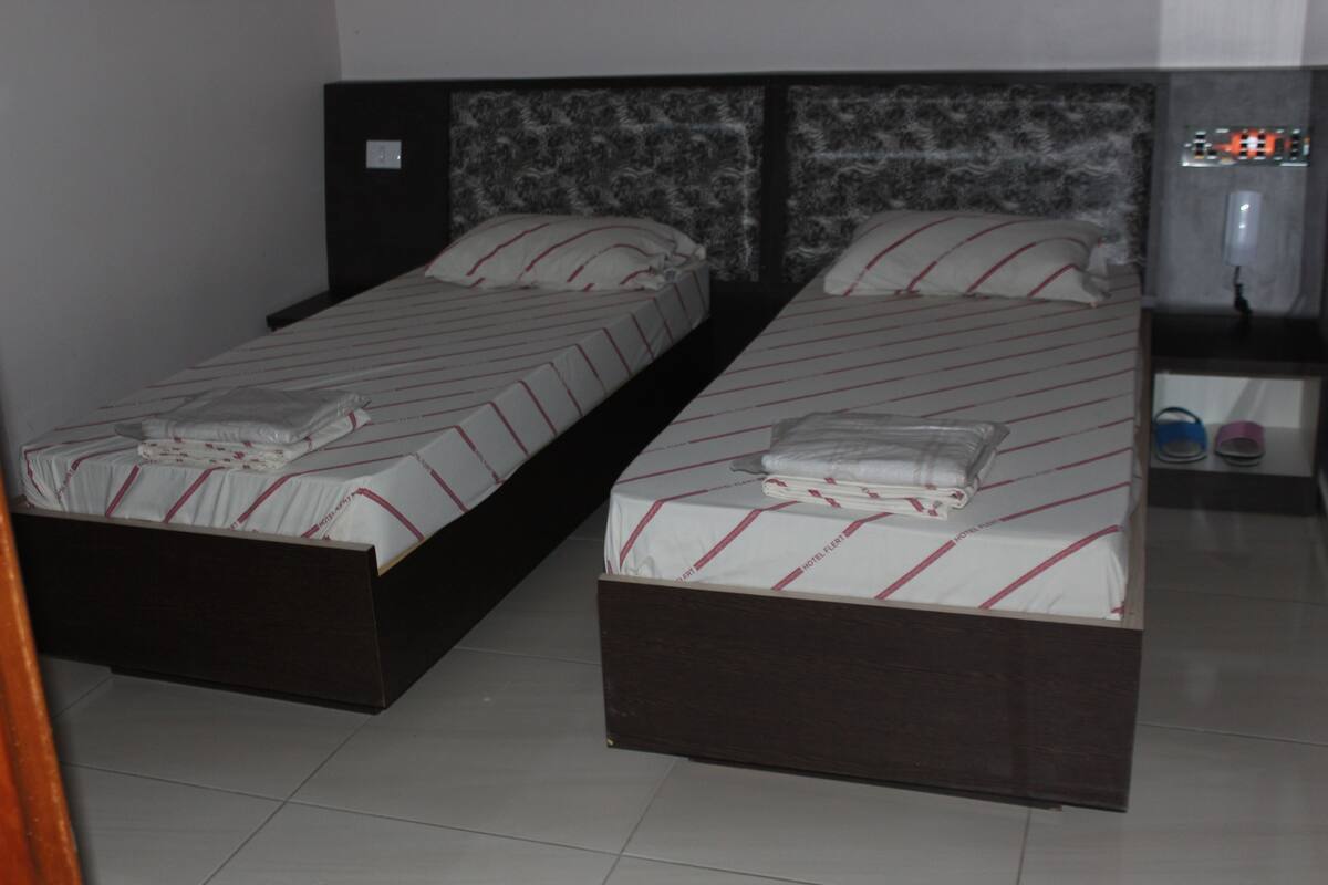 A room with two single beds, each with a wooden frame and a headboard with a textured pattern.