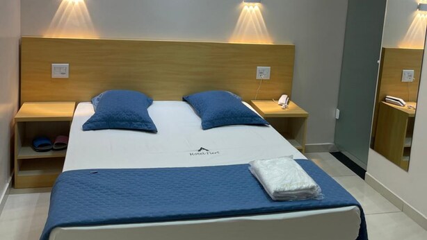 A hotel room with a large bed, two bedside tables, a nightstand, and a mirror. - Hotel Flert Tatuape (São Paulo)