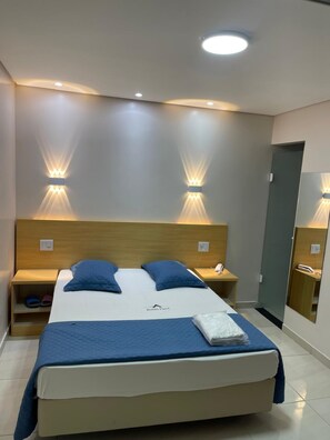 A hotel room with a large bed, two bedside tables, a nightstand, and a mirror. - Hotel Flert Tatuape (São Paulo)
