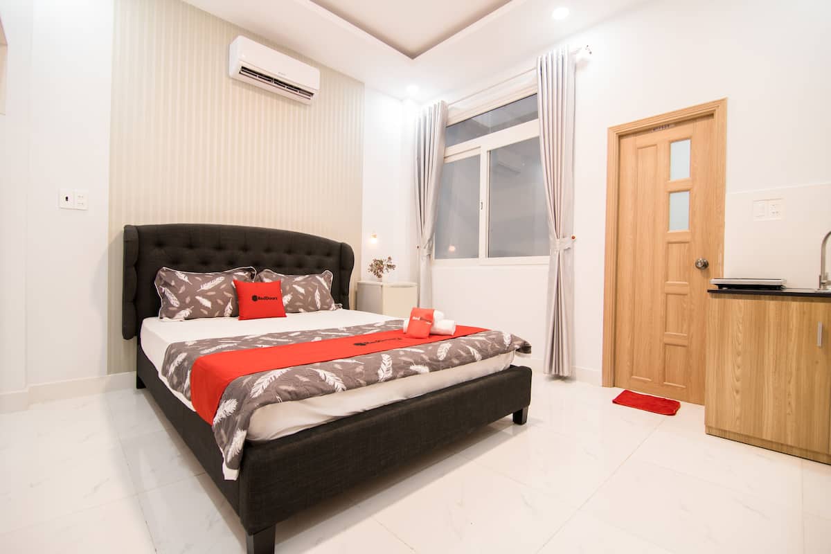Een netjes ingerichte slaapkamer met een groot bed, een houten deur en een airconditioning aan de muur.