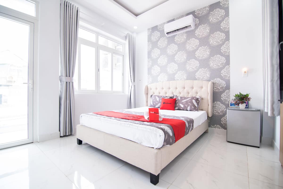 Een moderne slaapkamer met een groot bed, een klein nachtkastje, een airconditioning en uitzicht door een raam.
