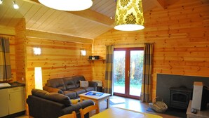 A cozy cabin interior with a living room, dining area, kitchen, and a fireplace. - Abri Vert (Viroinval)