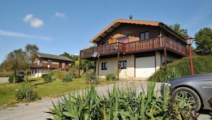 Une maison à deux étages avec un balcon, une antenne parabolique et une voiture garée devant.