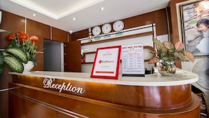 Un mostrador de recepción con un cartel de RedDoorz, un reloj y un menú enmarcado.