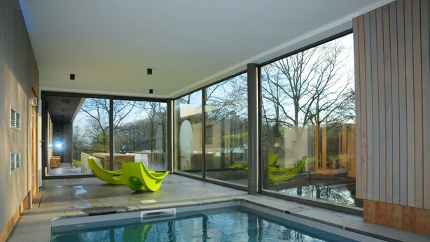A modern indoor swimming pool with clear glass walls, a bright interior, and a view of the outdoors. - Ard'cube (Somme-Leuze)