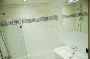 A bathroom with a shower, a sink, and a mirror.