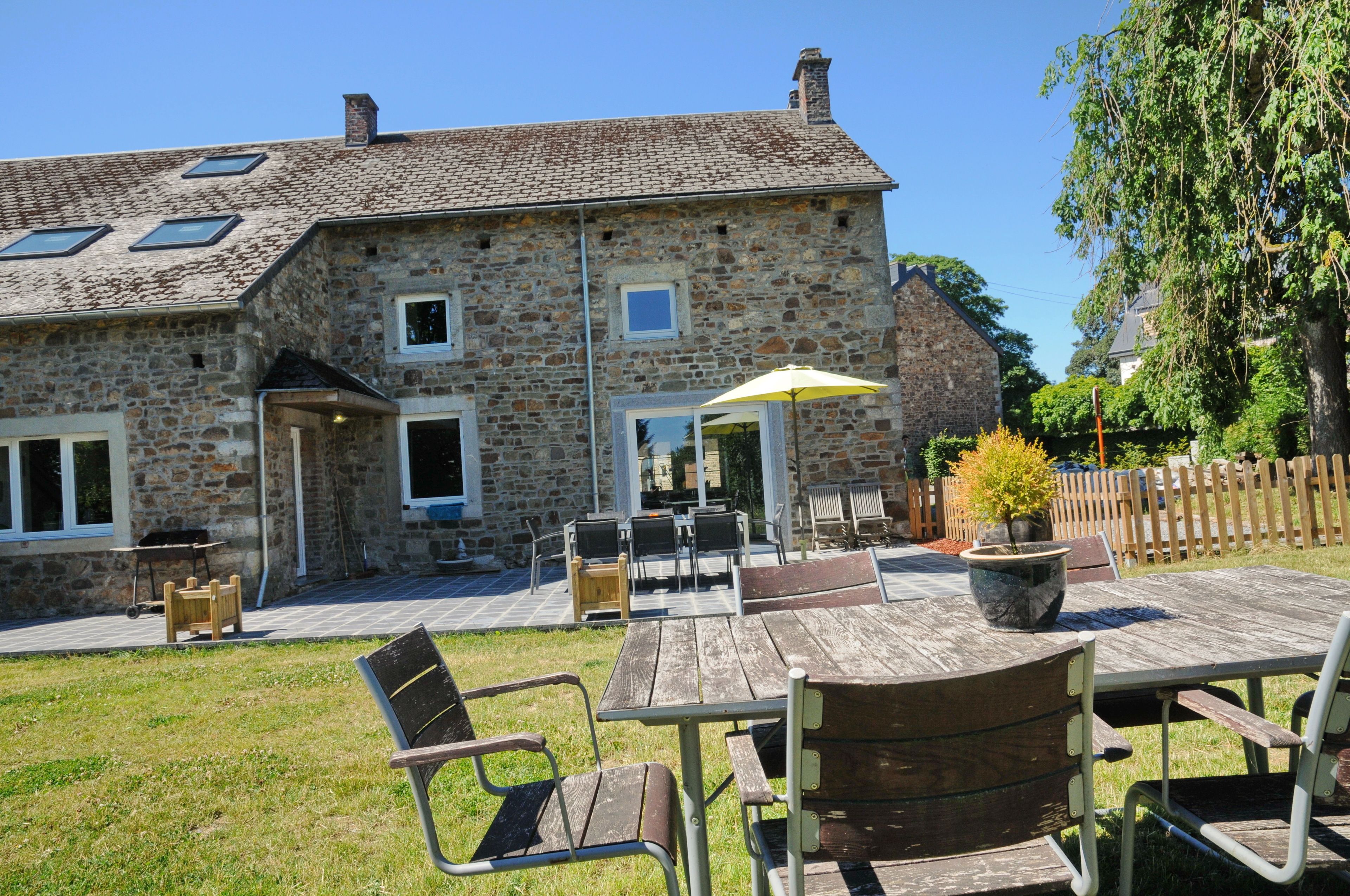 A stone building with a patio area featuring outdoor furniture and a table.