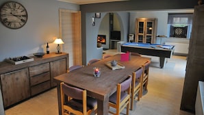 A dining area with a pool table, a clock, and a fireplace. - Au Phil du Temps (Erezee)