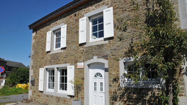 A stone building with white shutters, a door, and a small balcony. - Au Phil du Temps (Erezee)