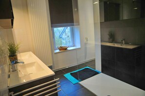 A modern bathroom with a large sink, a window, and a separate shower area.