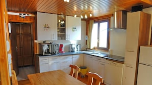 Cocina compacta con armarios de madera, un lavamanos, cafetera y refrigerador.