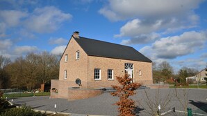 A brick building with a sloped roof, a large window, and a small door.