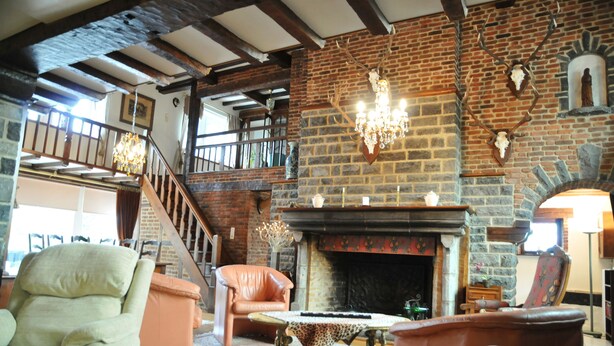 A spacious living room with a fireplace, leather sofas, and a staircase leading to an upper level. - Bourrasques (Marche-en-Famenne)