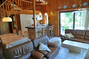 Een gezellig interieur van een chalet met een eethoek, een woonkamer met een bank en salontafel, en een keuken.