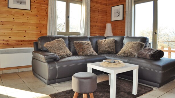 Ein modernes Wohnzimmer mit einem Ledersofa, einem weißen Couchtisch und einem runden Ottomanen.