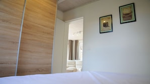 A hotel room with a wooden panel wall, a bed, and two framed quotes on the wall. - Chalet d'aventures (Durbuy)
