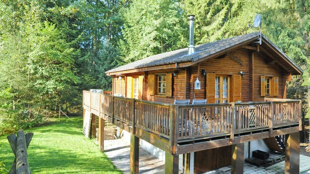 A wooden cabin with a balcony, surrounded by trees. - Chalet Mady (Erezee)
