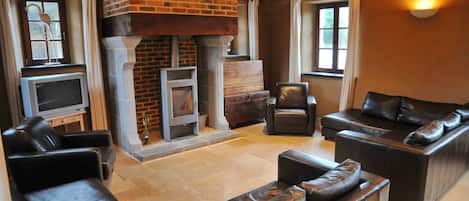 A living room with leather sofas, a fireplace, and a television.