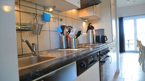 Eine moderne Küche mit Spülbecken aus Edelstahl, Backofen und Kaffeemaschine.