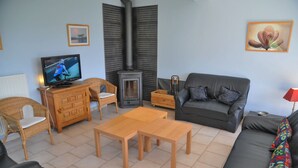 Ein Wohnzimmer mit Fernseher, Kamin, Sofa, Couchtisch und Esstisch.
