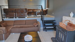 Ein modernes Wohnzimmer mit einem braunen Ecksofa, einem Couchtisch mit einer Dekoration, einem Korbwäscheschrank und einem Kamin mit Marmorverkleidung.