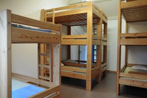 Camas individuales superpuestas con estructura de madera y ropa de cama azul.