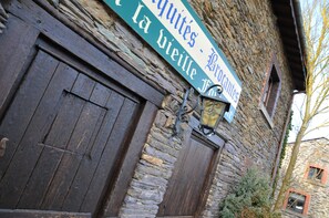 A stone building with a wooden door and a sign above it.