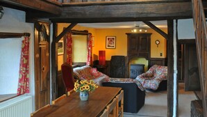 A rustic interior with a wooden dining table, chairs, a chandelier, and a staircase leading to an upper level. - Fermette Arbrefontaine (Lierneux)