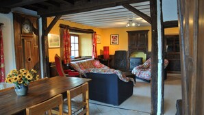 A traditional room with a wooden table, a sofa, and a clock on the wall. - Fermette Arbrefontaine (Lierneux)