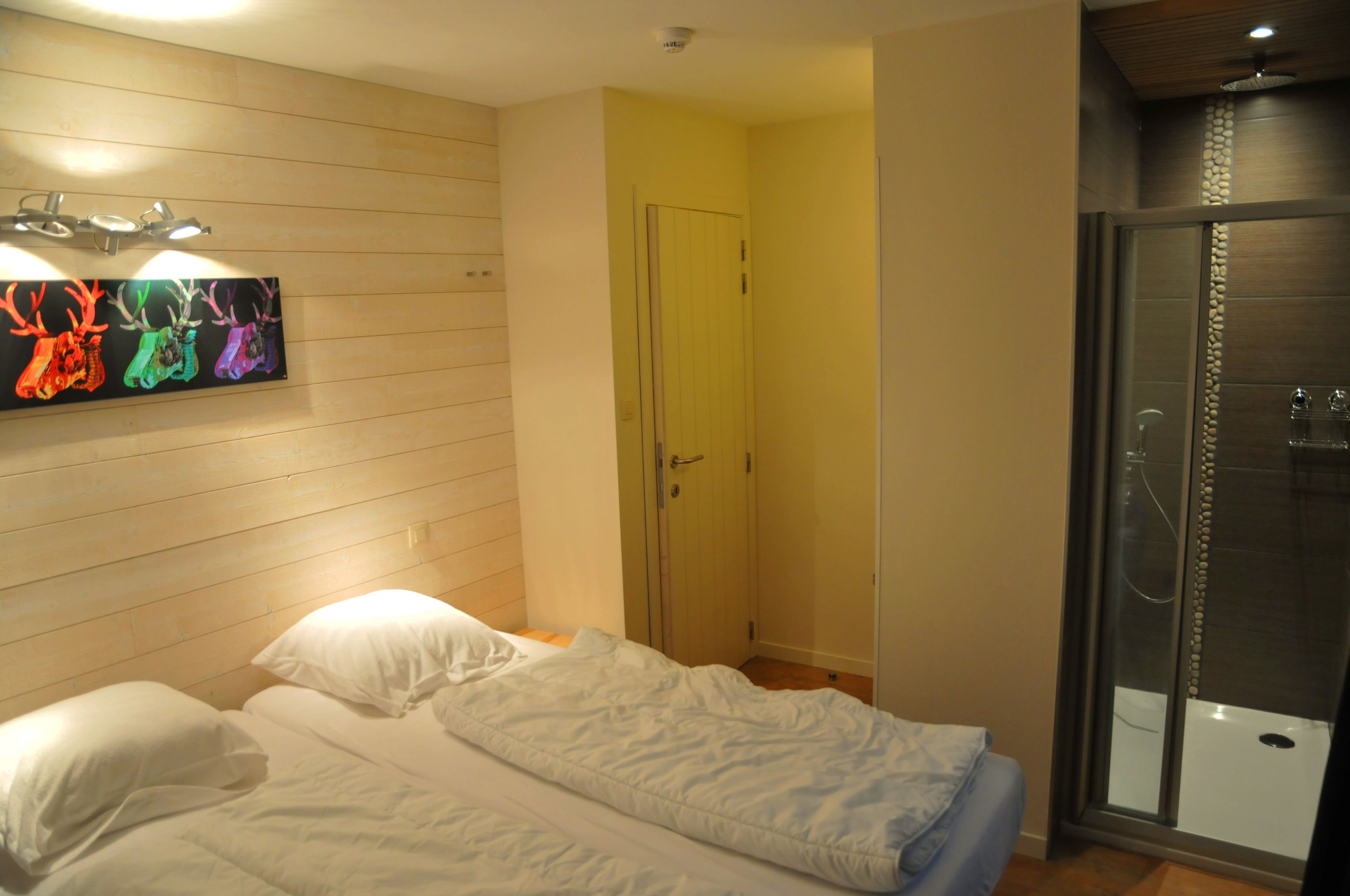 Een slaapkamer met een bed, een deur en een douchehoek.