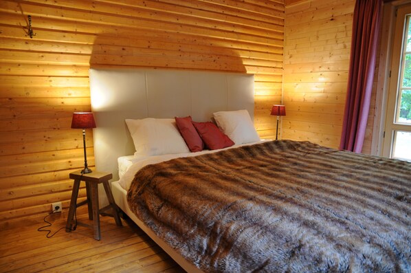 Una stanza con rivestimento in legno, un letto, due lampade da comodino e una finestra con tende.