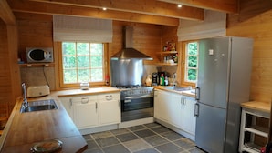 Cocina compacta con paredes de madera, estufa de acero inoxidable, microondas y refrigerador.