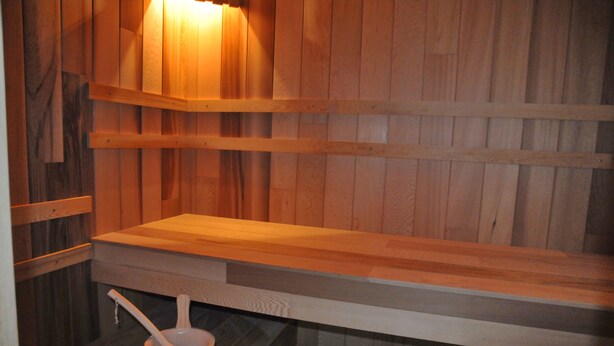 A wooden sauna with benches and a bucket with a brush.