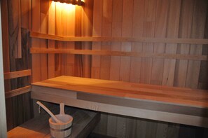 Una sauna de madera con bancos y un cubo con un cepillo.