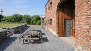 A brick building with a wooden door and a covered outdoor area with picnic tables.
