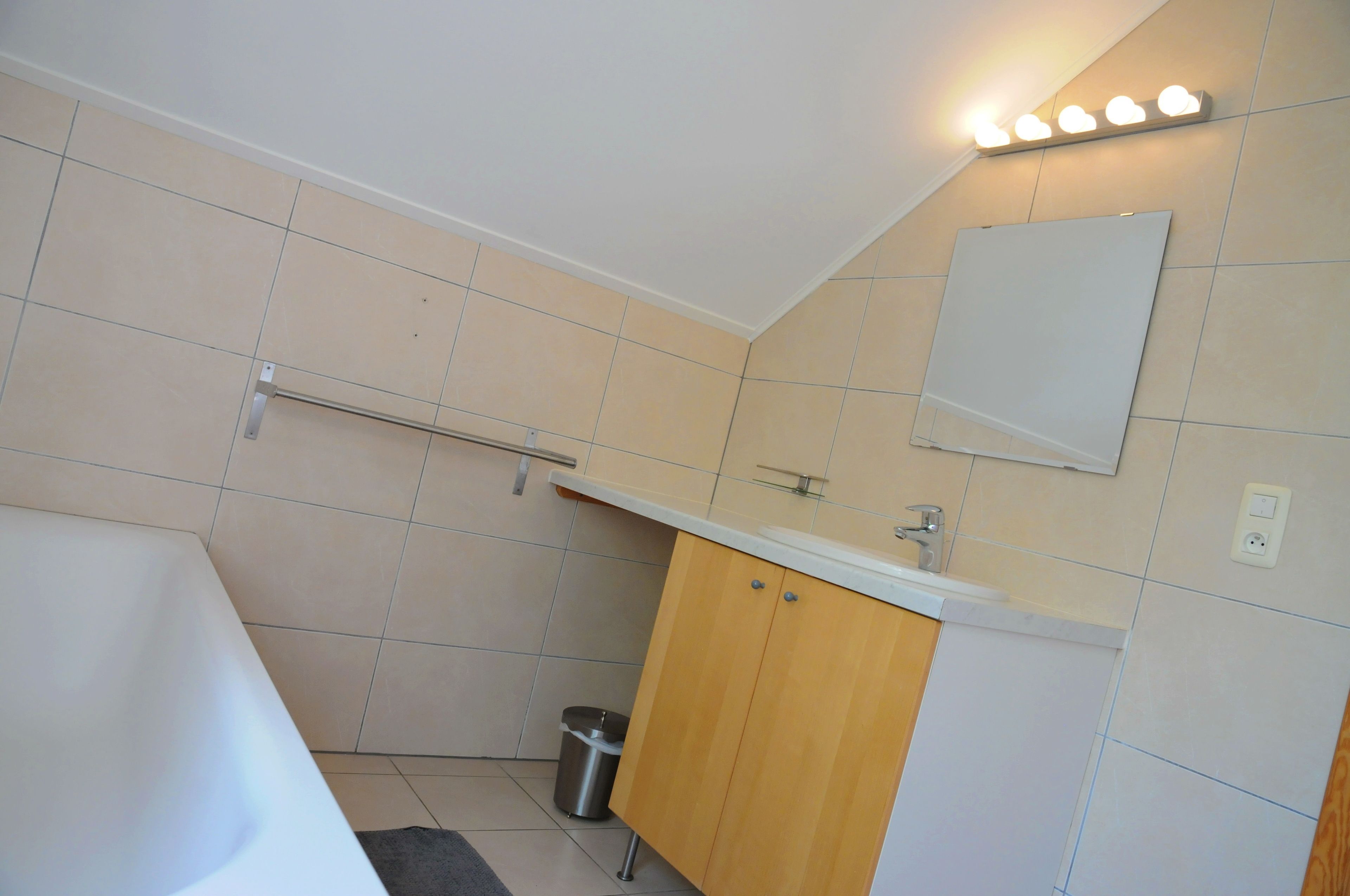 Un baño con una bañera blanca, tocador de madera y un espejo.