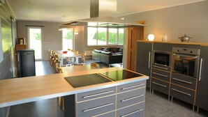 Una cocina moderna con una isla central, horno empotrado y un comedor con sofá y mesa.