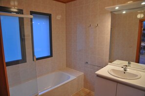 A bathroom with a bathtub, a sink, and a mirror.