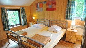 Un lit double avec un cadre en métal, une table de chevet avec des tiroirs, une lampe et une fenêtre avec des rideaux.